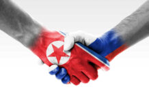 Two hands shaking with flags painted on them.