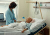 Hospital patient in bed with a visitor watching