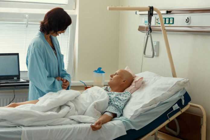 Hospital patient in bed with a visitor watching