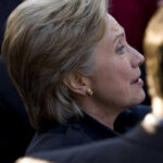 Person with short blonde hair, wearing gold earrings.