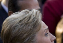 Person with short blonde hair, wearing gold earrings.