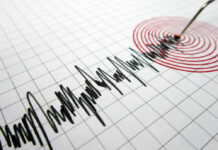 Seismograph needle recording earthquake on graph paper.
