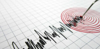Seismograph needle recording earthquake on graph paper.
