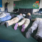 Group of individuals lying on the floor in a classroom during an exercise