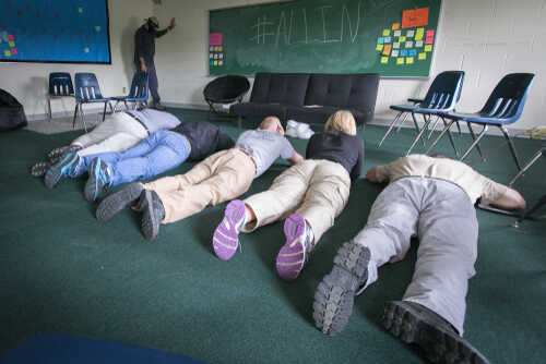 Group of individuals lying on the floor in a classroom during an exercise