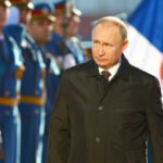 A political figure walking past a military honor guard during a ceremony
