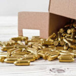 A cardboard box spilling golden bullets onto a wooden surface