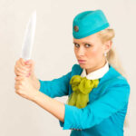 A flight attendant holding a knife in a dramatic pose