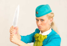 A flight attendant holding a knife in a dramatic pose