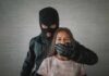 A masked figure holding a girl, covering her mouth