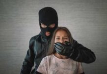 A masked figure holding a girl, covering her mouth