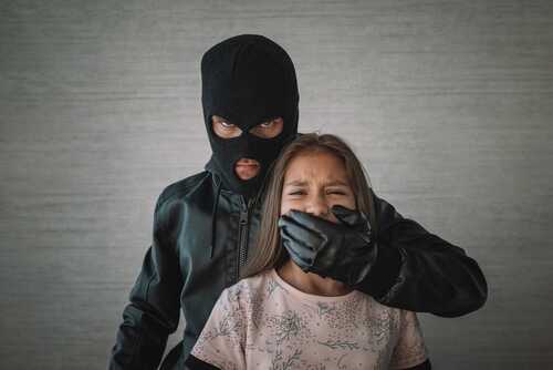 A masked figure holding a girl, covering her mouth
