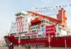 A large red research vessel docked with festive decorations and banners