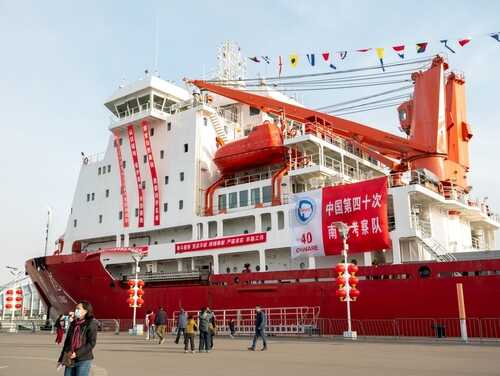 shutterstock_2449062101 (1).jpg A large red research vessel docked with festive decorations and banners