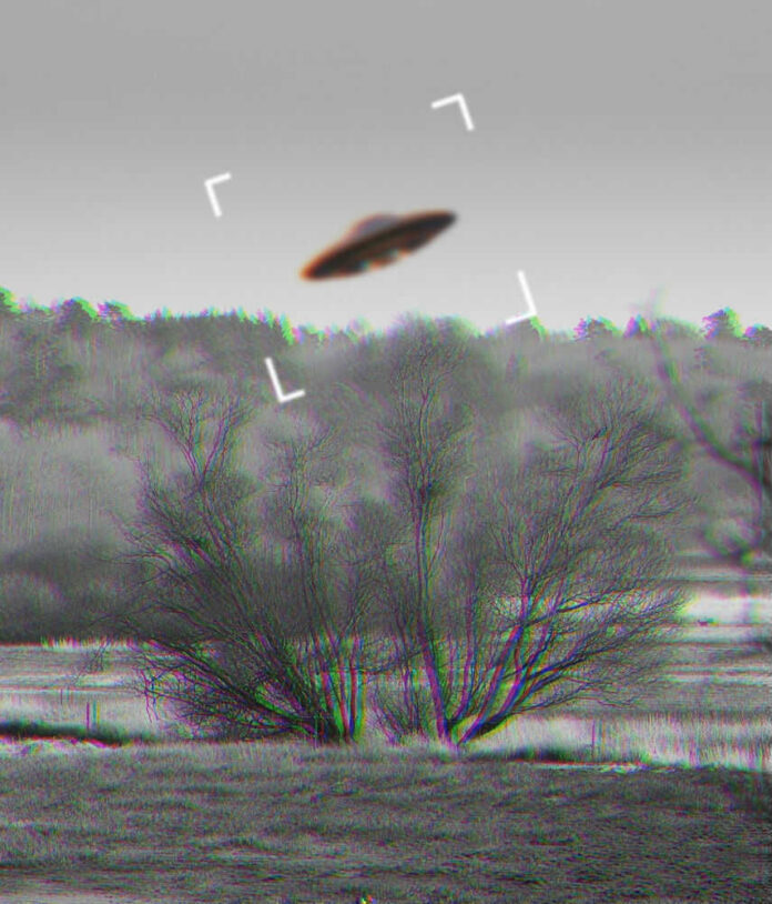 Black and white UFO over forest landscape.