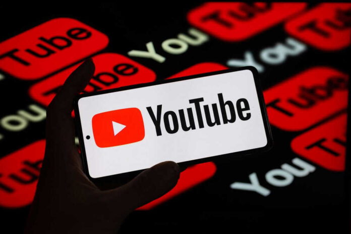 Hand holding phone showing YouTube logo.