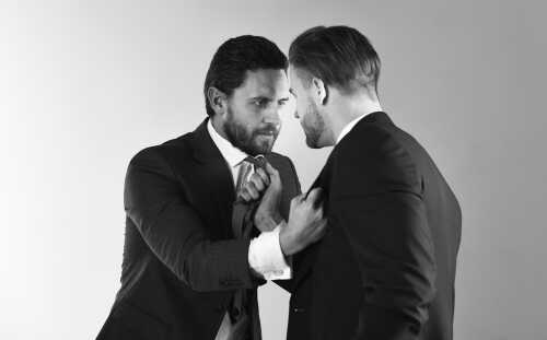 Two men in suits engaged in a tense confrontation