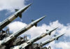 Array of military missiles against a blue sky with clouds