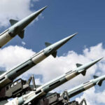 Array of military missiles against a blue sky with clouds