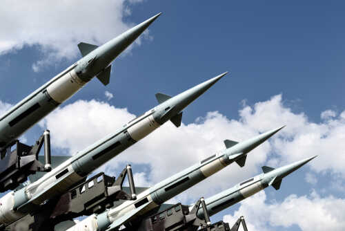 Array of military missiles against a blue sky with clouds
