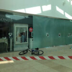 Daring Window Smash Stuns Flooded Tennessee Damaged storefront with broken glass and an abandoned bicycle in front