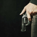 Close-up of a hand holding a revolver against a dark background