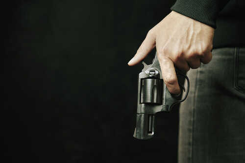 Close-up of a hand holding a revolver against a dark background