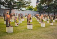 A memorial site with numerous sculptures and flowers in a grassy area