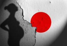 Silhouette of a pregnant woman against a textured wall with a red circle
