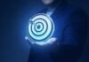A person holding a glowing target with an arrow in the center