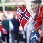 Royal Rape Charges Ignite Norway’s Fury Person in traditional Norwegian attire holding a small flag during a celebration