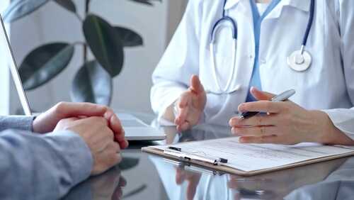 A doctor discussing with a patient over a clipboard in a medical office