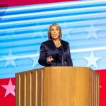 Crime Wave EXPLODES — Governor Declares EMERGENCY A woman delivering a speech at a podium with an American flag backdrop