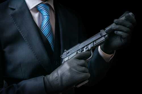 shutterstock_481840897.jpg A person in a suit holding a handgun