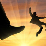 Trump’s Visa Purge: 6,000 Students Expelled Silhouette of a person falling beneath a giant shoe against a sunset