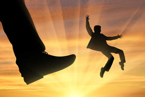 shutterstock_482188930.jpg Silhouette of a person falling beneath a giant shoe against a sunset