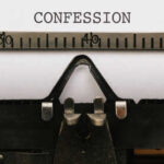 Close-up of a typewriter with the word 'CONFESSION' typed on paper