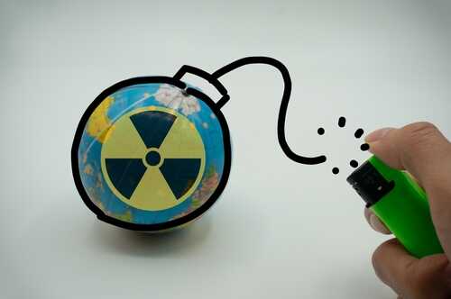 A hand holding a lighter next to a globe with a nuclear symbol drawn on it