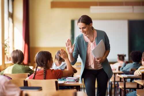 A teacher giving a high five to a student in a classroom
