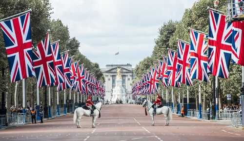 Two mounted guards in front of Buckingham Palace with British flags lining the street