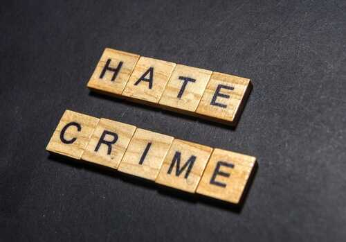Wooden letter tiles spelling 'HATE' and 'CRIME' on a dark background