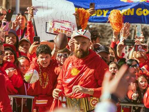 A crowd of enthusiastic fans celebrating with a football player in a festive atmosphere