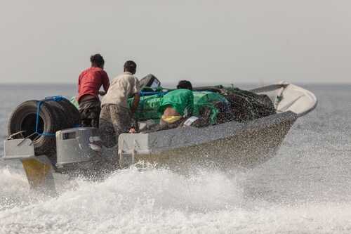 Fishermen on a boat navigating through ocean waves