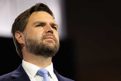 A man in a suit with a focused expression speaking at a conference