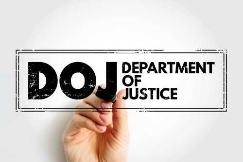 Hand holding a marker writing DOJ Department of Justice