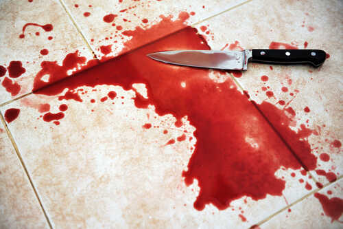 A bloody knife lying next to a pool of blood on tiled flooring