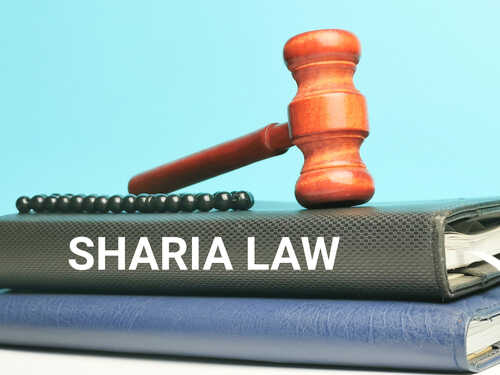 A wooden gavel resting on top of law books with 'Sharia Law' printed on the cover