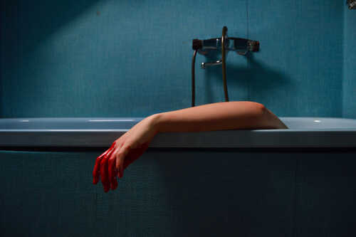 A disembodied arm with red paint emerging from a bathtub