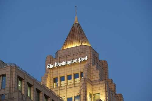 The top of a building featuring the sign of The Washington Post against a twilight sky