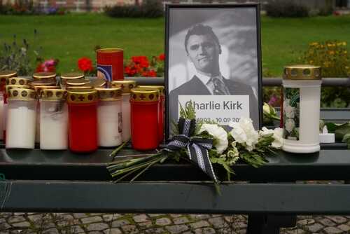 Memorial setup with candles, flowers, and a portrait of a man